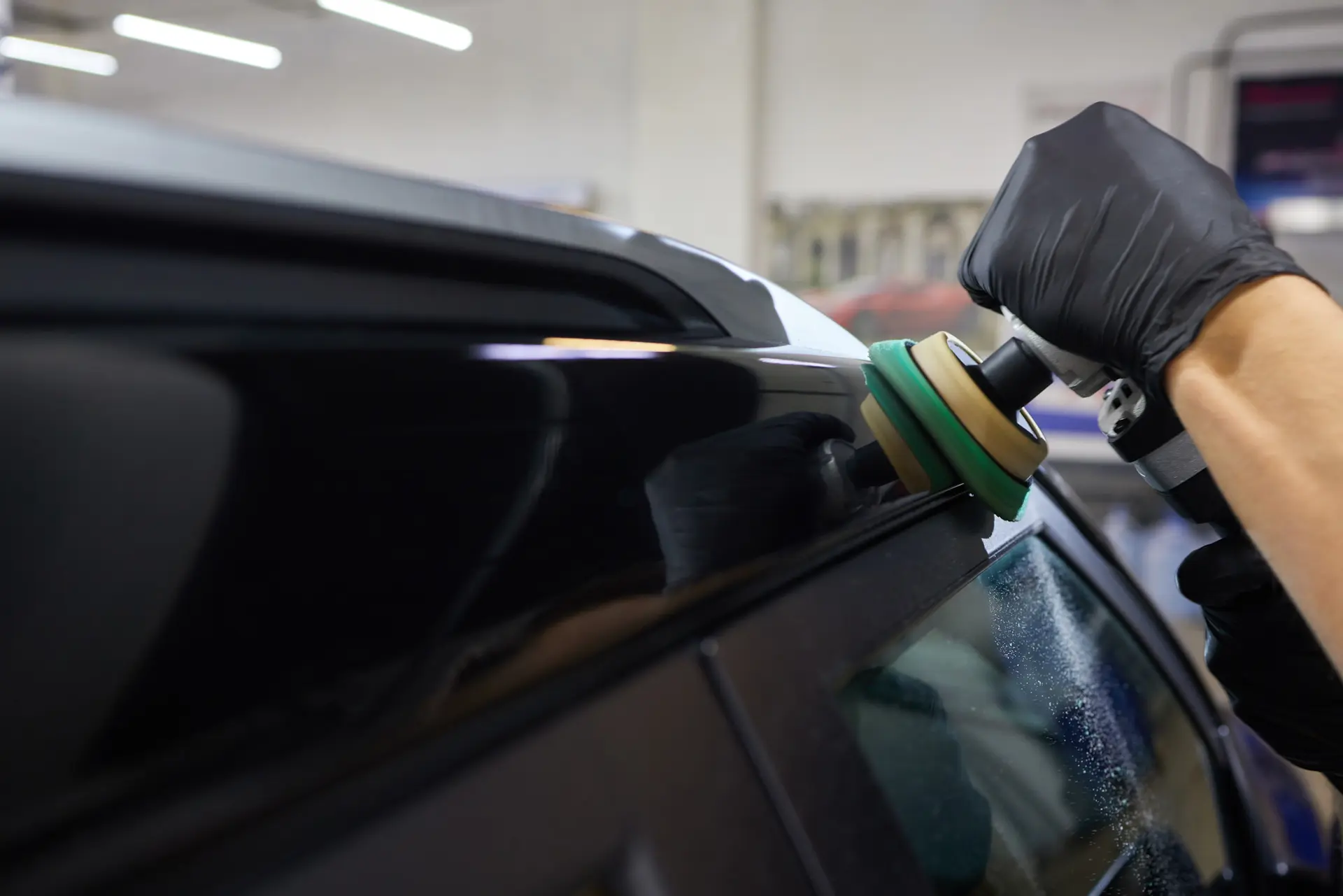 Man with orbital polisher car workshop polishing car closeup edited